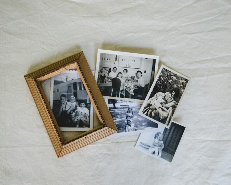 Black-and-white family photographs arranged beside a wooden picture frame.