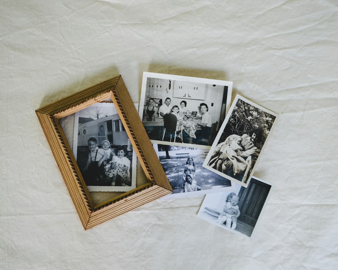 Black-and-white family photographs arranged beside a wooden picture frame.