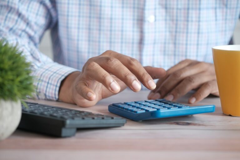 Hands using a calculator at a desk.