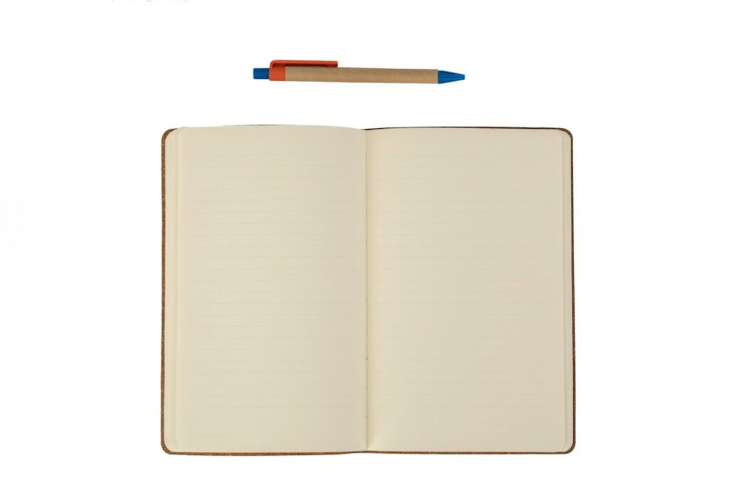 An open lined notebook and a pen on a white surface.