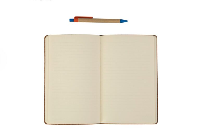 An open lined notebook and a pen on a white surface.