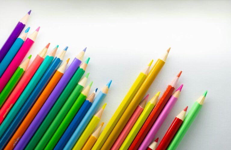 Colored pencils arranged diagonally on a white surface.