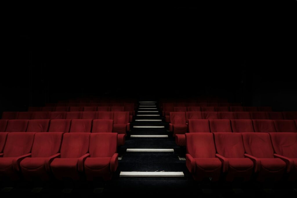 Rows of empty red cinema seats beside a central aisle