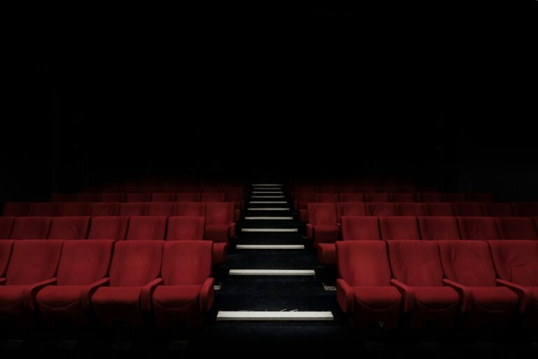 Rows of empty red cinema seats beside a central aisle