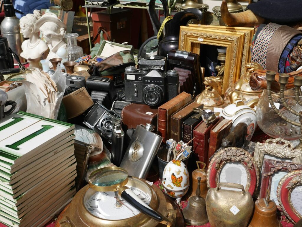 Secondhand cameras, books, picture frames and household objects on a flea-market stall.