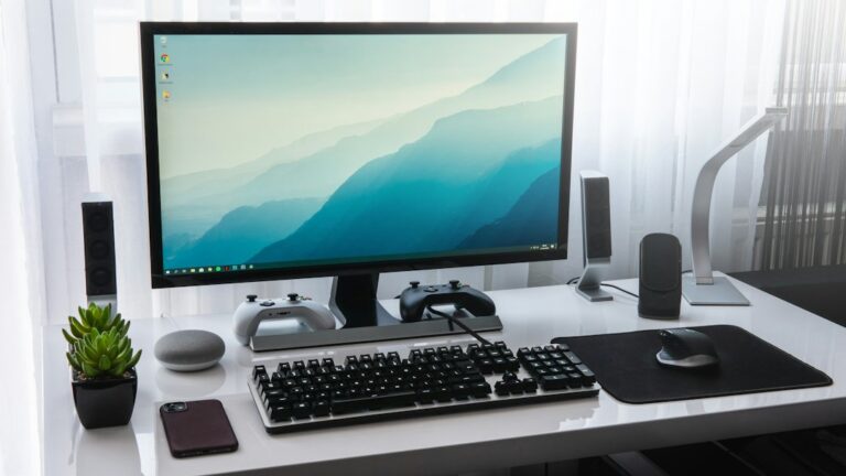 A desktop monitor, keyboard, and mouse on a white desk.