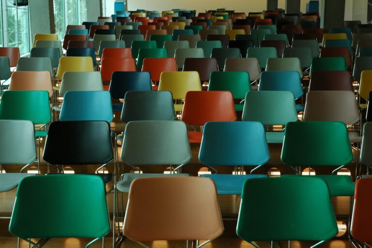 Rows of empty multicolored chairs in a bright room.