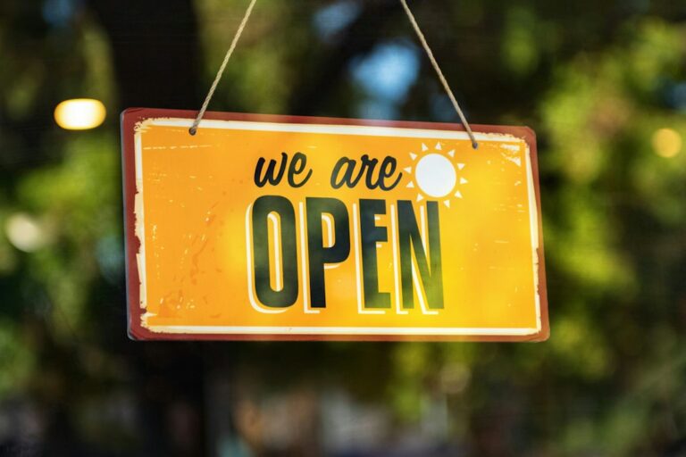 A yellow sign reading We are open hanging in a window.