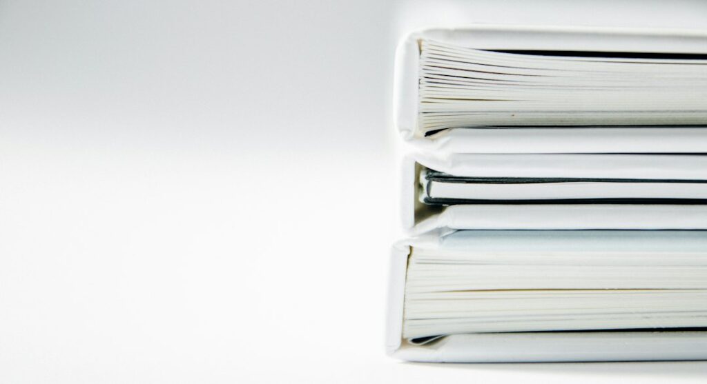 Three white-covered volumes stacked on a white surface.