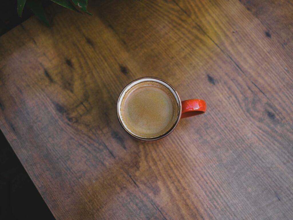 A red coffee mug viewed from above on a wooden table.