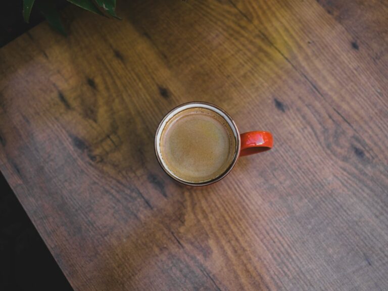 A red coffee mug viewed from above on a wooden table.