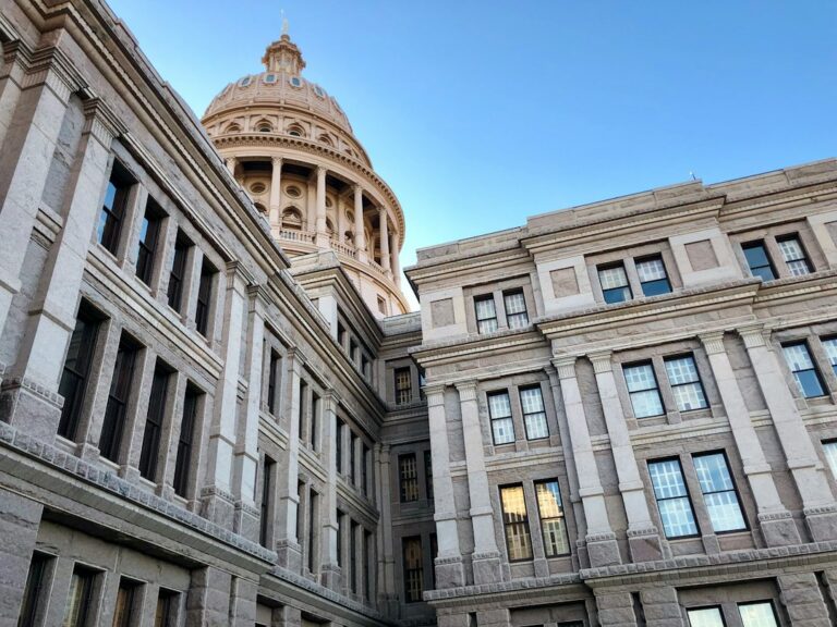 The Texas State Capitol dome and stone exterior under a blue sky.