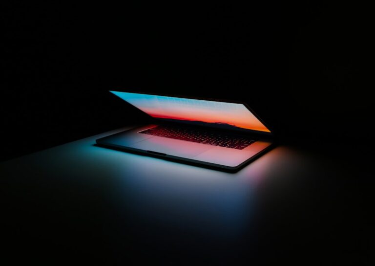Partly closed laptop with a colorful screen in a dark room.