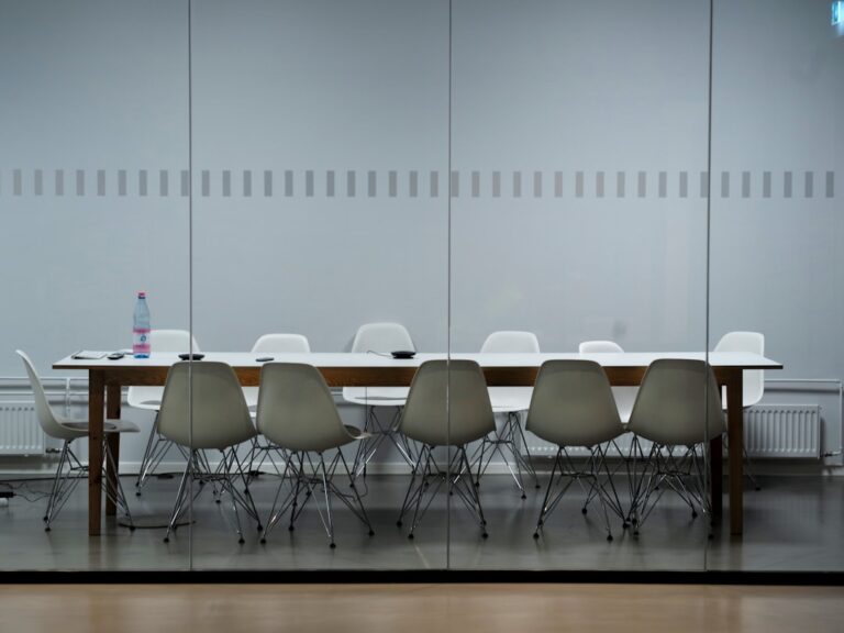 White and grey chairs around a long table in an empty meeting room.