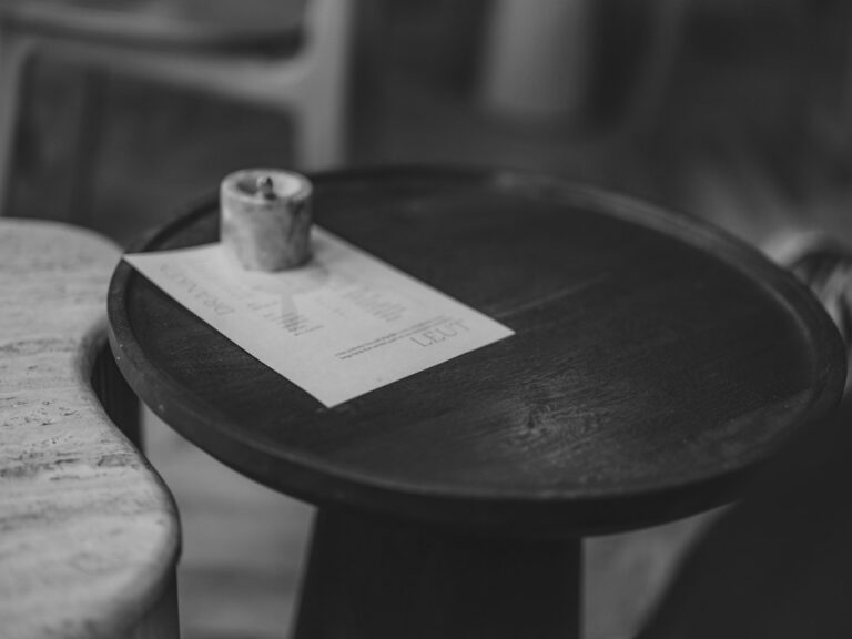A menu and a small candle on an empty round café table.
