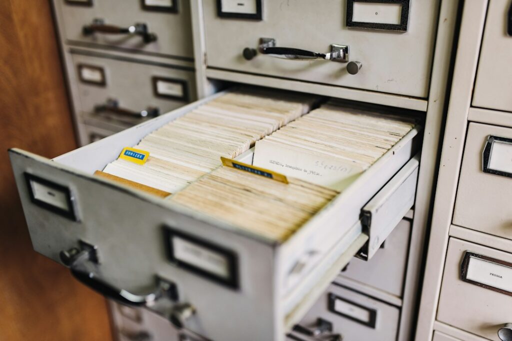 An open metal card-catalogue drawer containing rows of paper index cards.