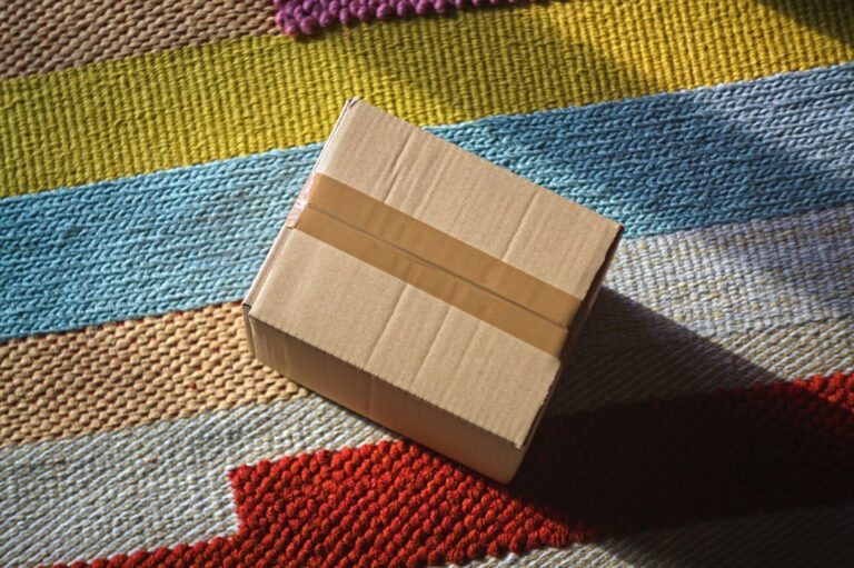 A sealed cardboard parcel resting on a multicoloured striped rug.
