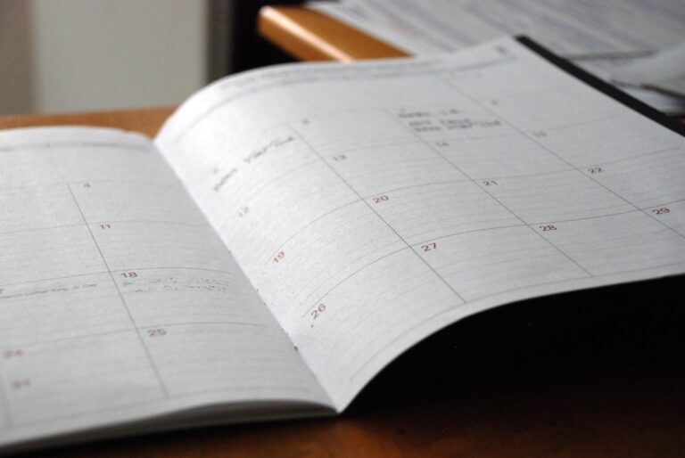 Open paper calendar on a wooden desk.