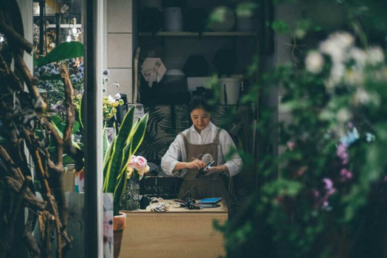 A florist working behind a counter surrounded by plants and flowers.