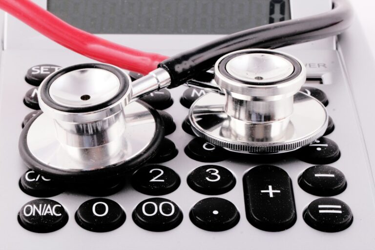 Two stethoscope chestpieces resting on a calculator.