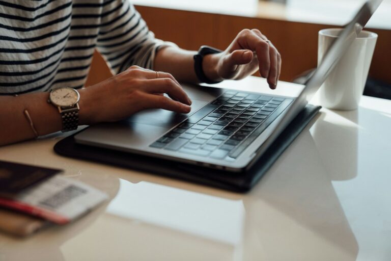 Hands typing on a laptop at a desk.
