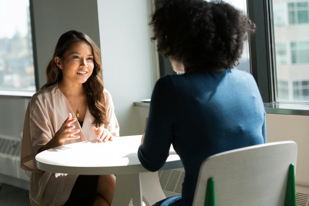 Two people talking across a table during a meeting.