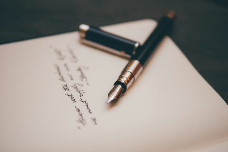 A fountain pen resting on paper with handwritten notes.