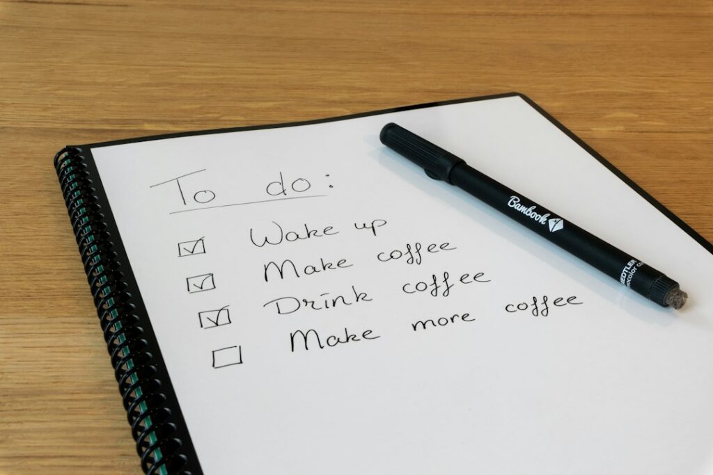 A handwritten checklist beside a pen on a wooden table.