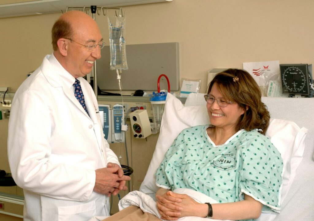 A doctor speaking with a patient seated in a hospital bed.