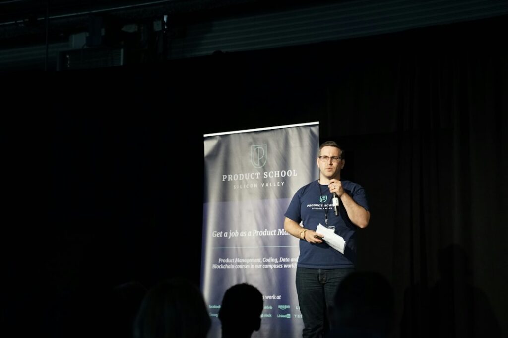 A speaker holding a microphone on a conference stage.