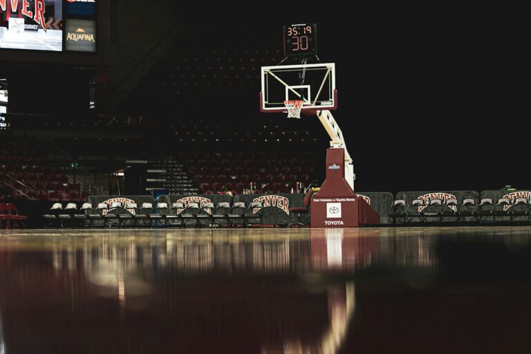 A basketball hoop and scoreboard above an empty indoor court.