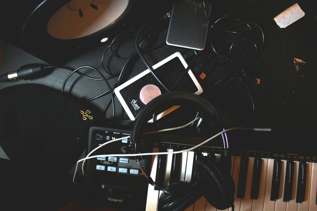 Headphones, a music keyboard, and audio equipment on a dark desk.