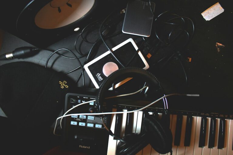 Headphones, a music keyboard, and audio equipment on a dark desk.