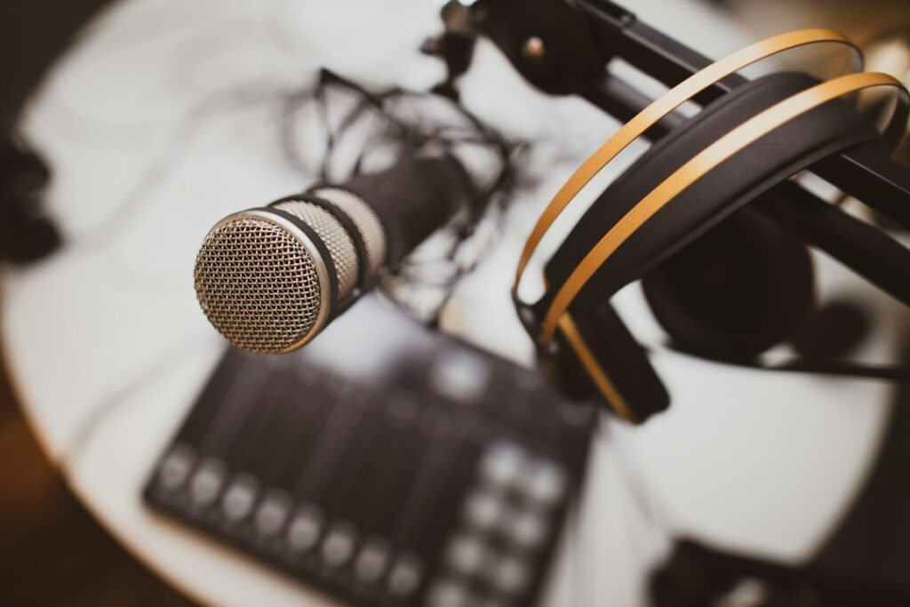A studio microphone and headphones above a podcast recording desk.