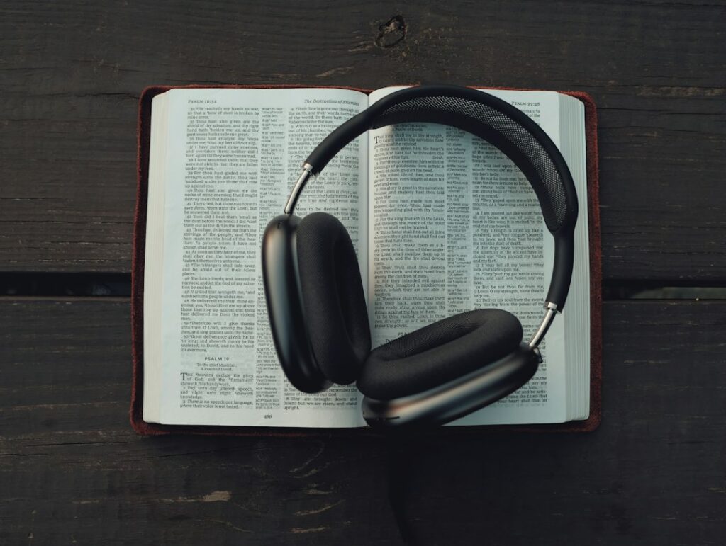 Black headphones resting on an open book on a wooden table.