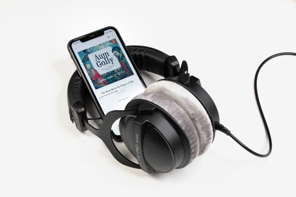 A smartphone displaying an audiobook beside wired headphones.