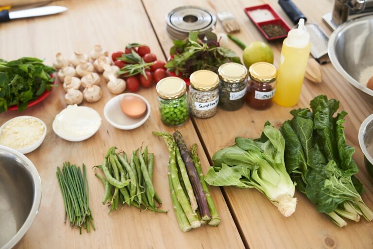 Vegetables, herbs, an egg and other ingredients arranged on a wooden kitchen worktop.