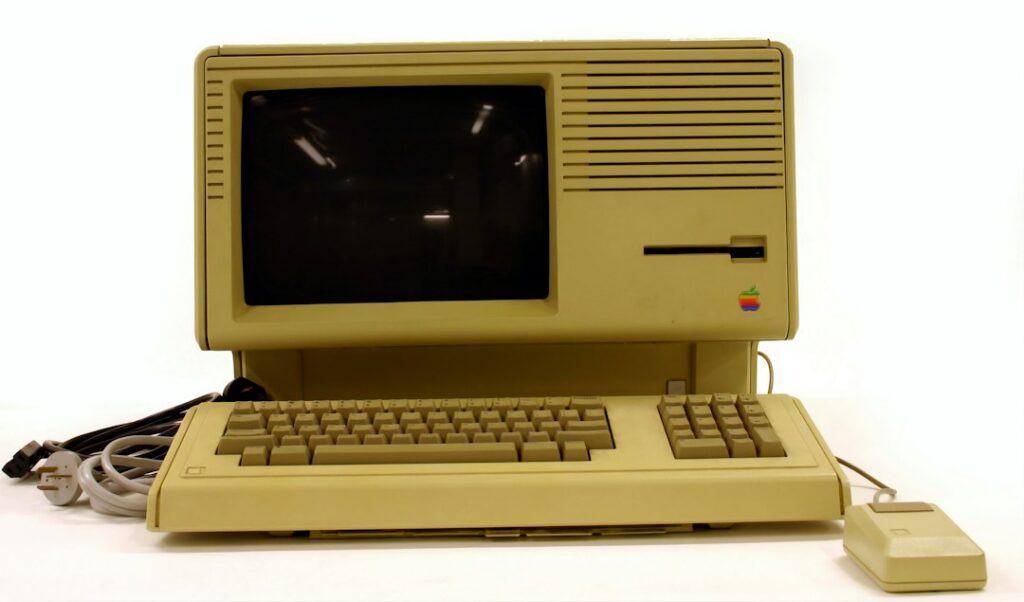 A vintage beige Apple computer with its keyboard, mouse, and cables.