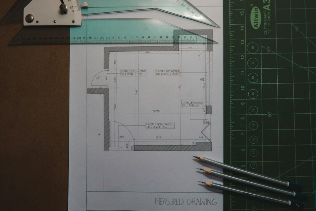 Measured room drawing with rulers and pencils on a cutting mat.