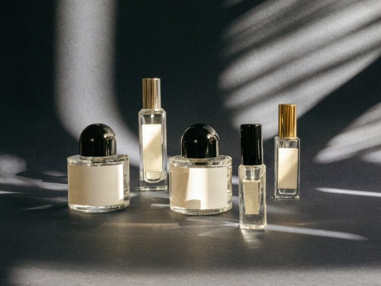 Five perfume bottles with simple labels arranged on a gray surface.