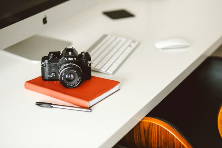 Camera on an orange notebook beside a desktop computer keyboard.