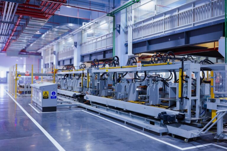 Industrial machinery and overhead pipes along a factory production line.