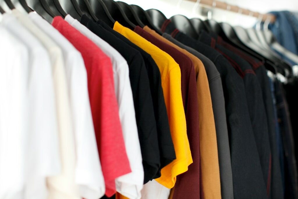 A row of colorful T-shirts hanging on a clothing rack.