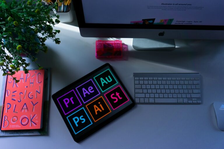 A design workspace with a computer, keyboard, books and a tablet.
