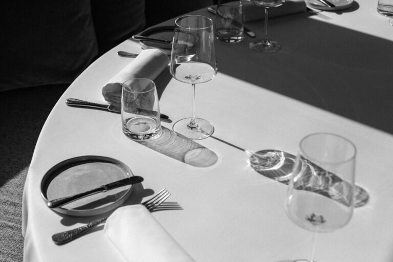 Empty wine glasses, plates and cutlery on a white restaurant table