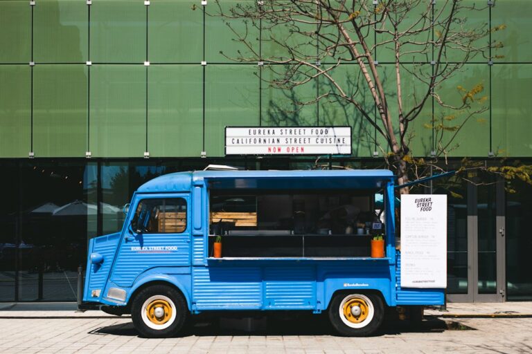 Blue street-food truck with an open serving window and a menu board.