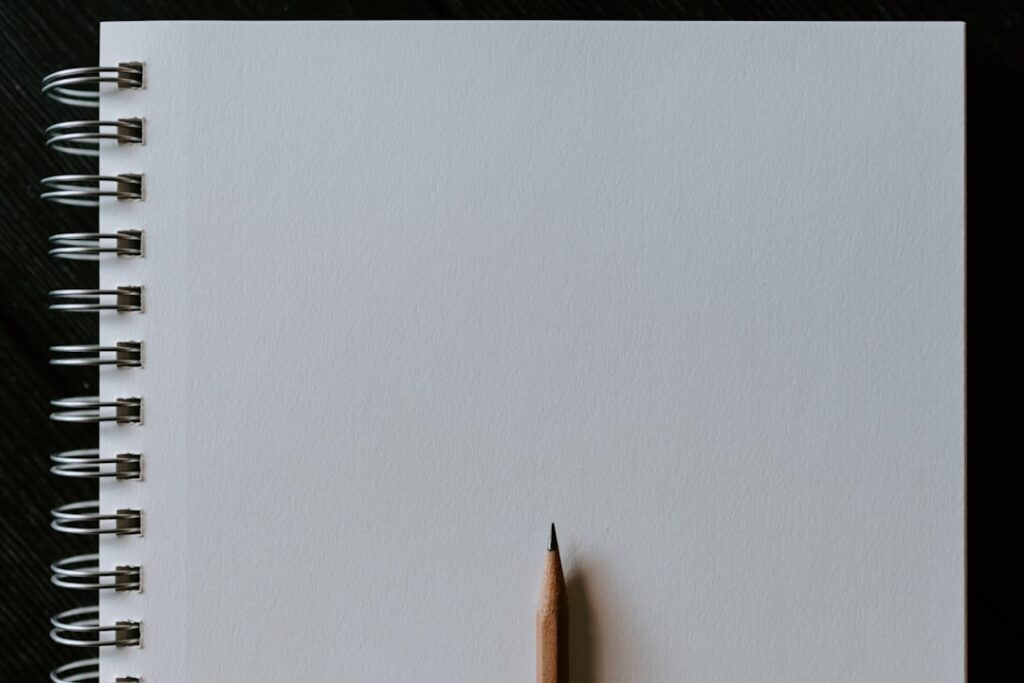 Blank spiral notebook with a sharpened pencil.