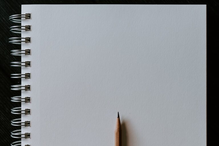 Blank spiral notebook with a sharpened pencil.