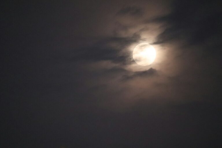 The moon shining through clouds at night
