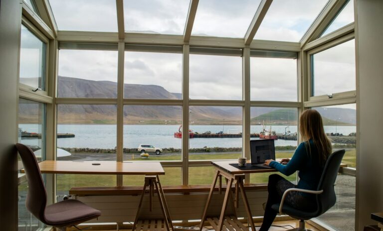 Person using a laptop at a desk overlooking a harbor in Iceland